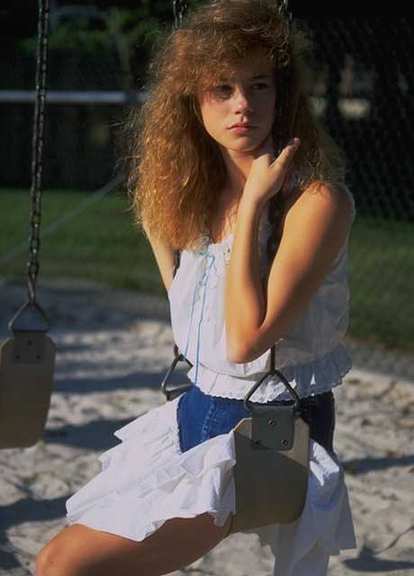 Mujer con rostro abstraido y triste en un columpio